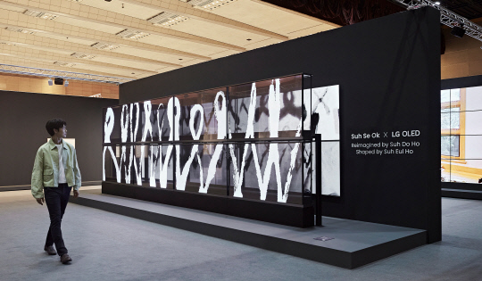 LG전자가 '프리즈 서울 2024'에서 수묵 추상화 거장 고 서세옥 화백의 작품을 그의 두 아들이 재해석한 미디어아트를 선보인다. 모델이 8대의 투명 올레드 TV와 8대의 올레드 에보로 구성한 미디어아트를 감상하고 있다. LG전자 제공